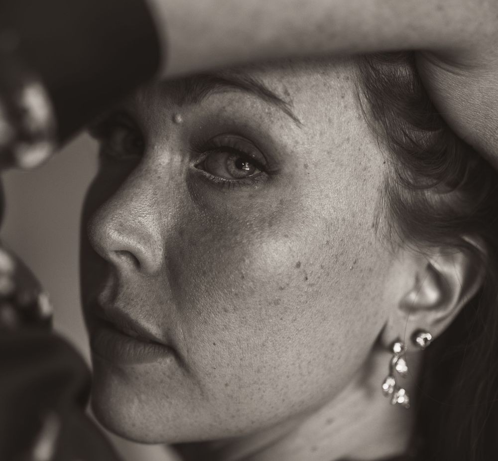 Vintage-style black and white portrait showing delicate features and dangling earring in dramatic lighting.