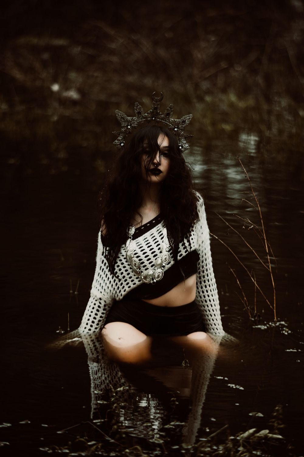 Gothic portrait in water featuring white crochet top and ornate crown in dark setting.