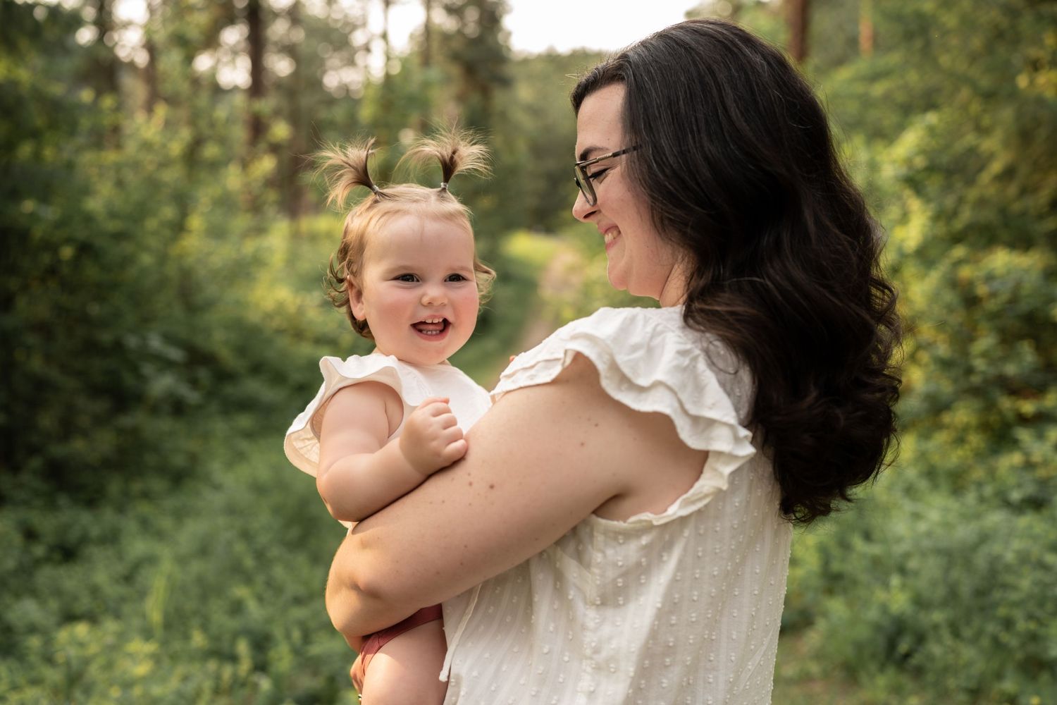 A tender moment between loved ones in a sunlit forest setting with natural greenery.