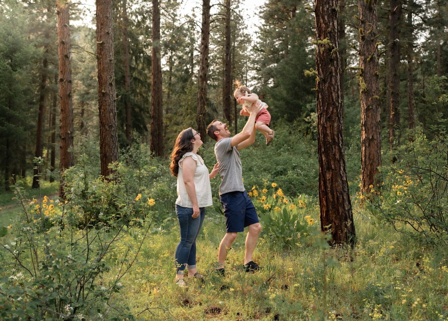 A group plays together in a sunlit forest meadow with yellow wildflowers.