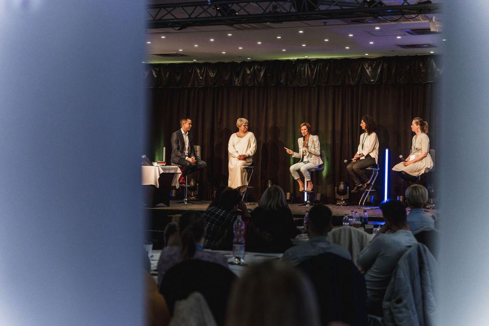 Panel discussion event with speakers seated on stage in front of audience.
