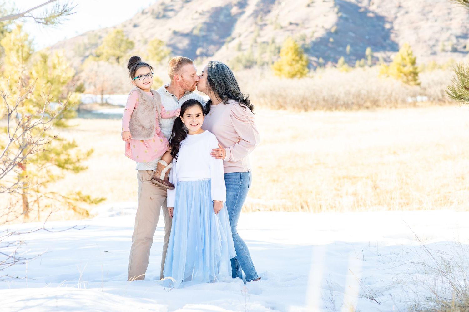 Parents kiss while their young daughters smile in Castle Rock, Colorado.