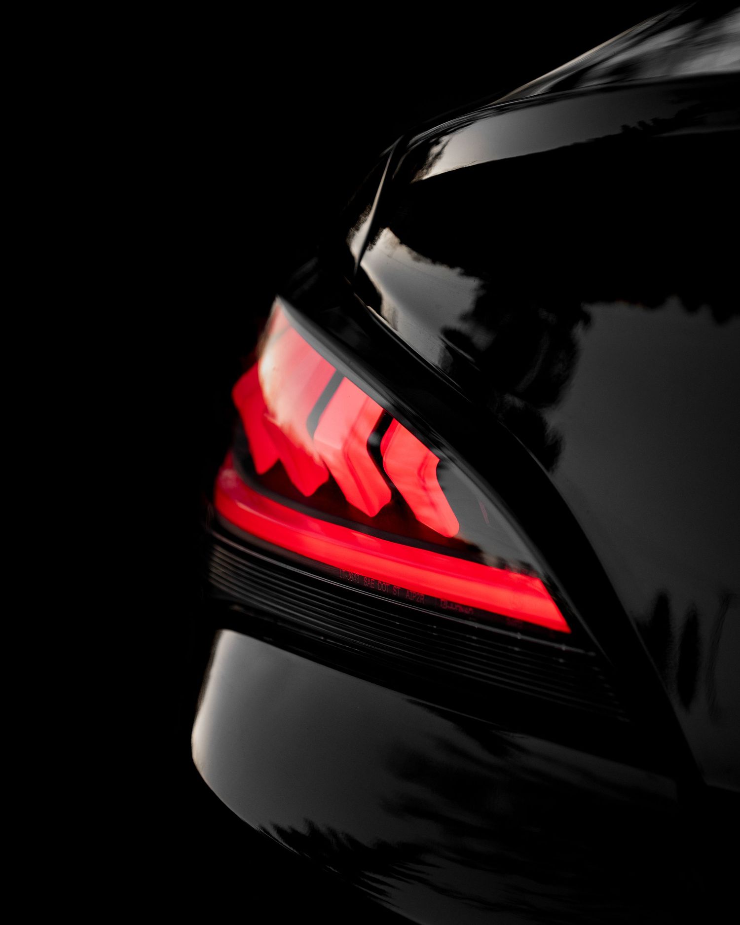 Close-up of modern LED taillights glowing red against black car exterior.