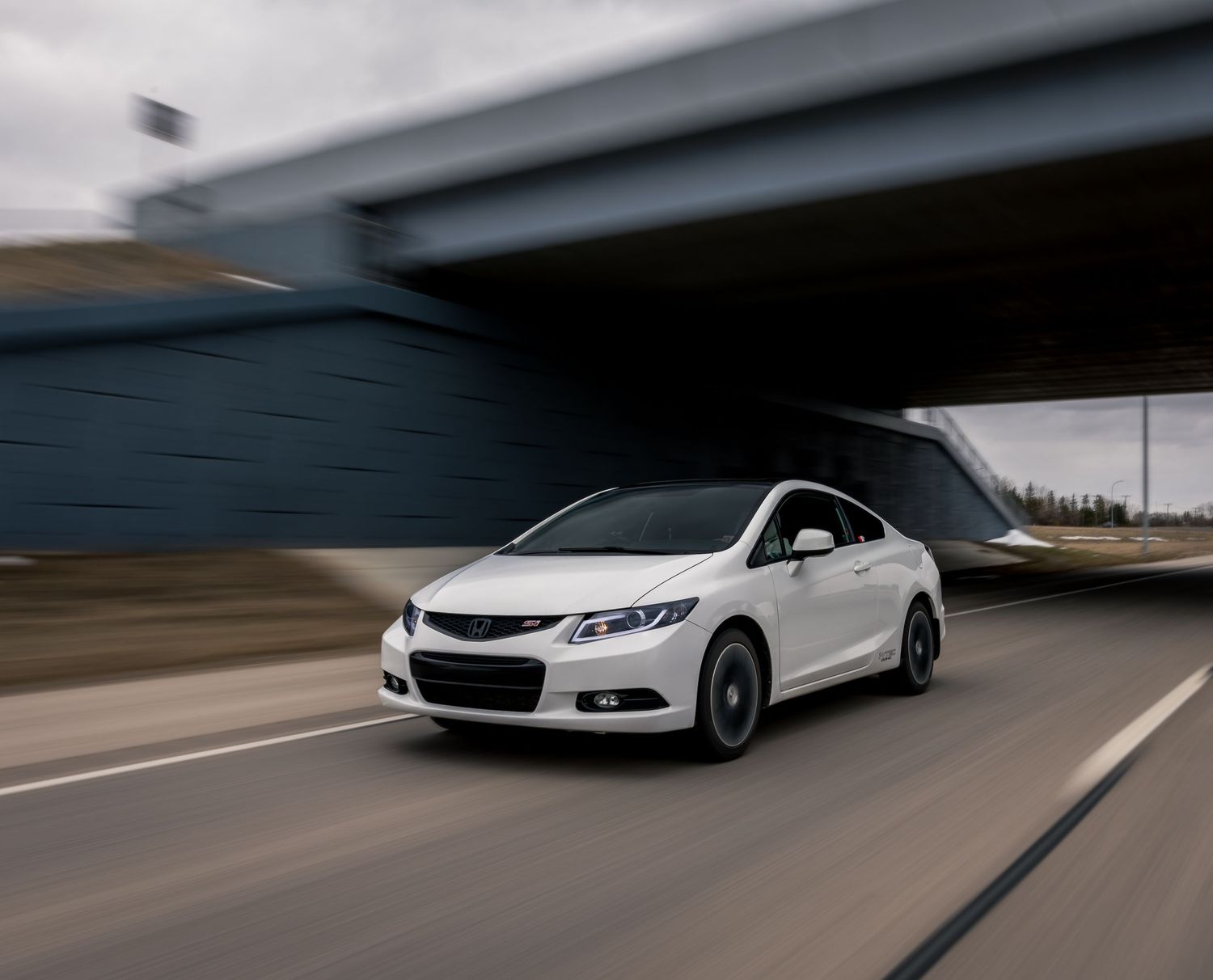 White Chevrolet Malibu in motion shot under overpass.