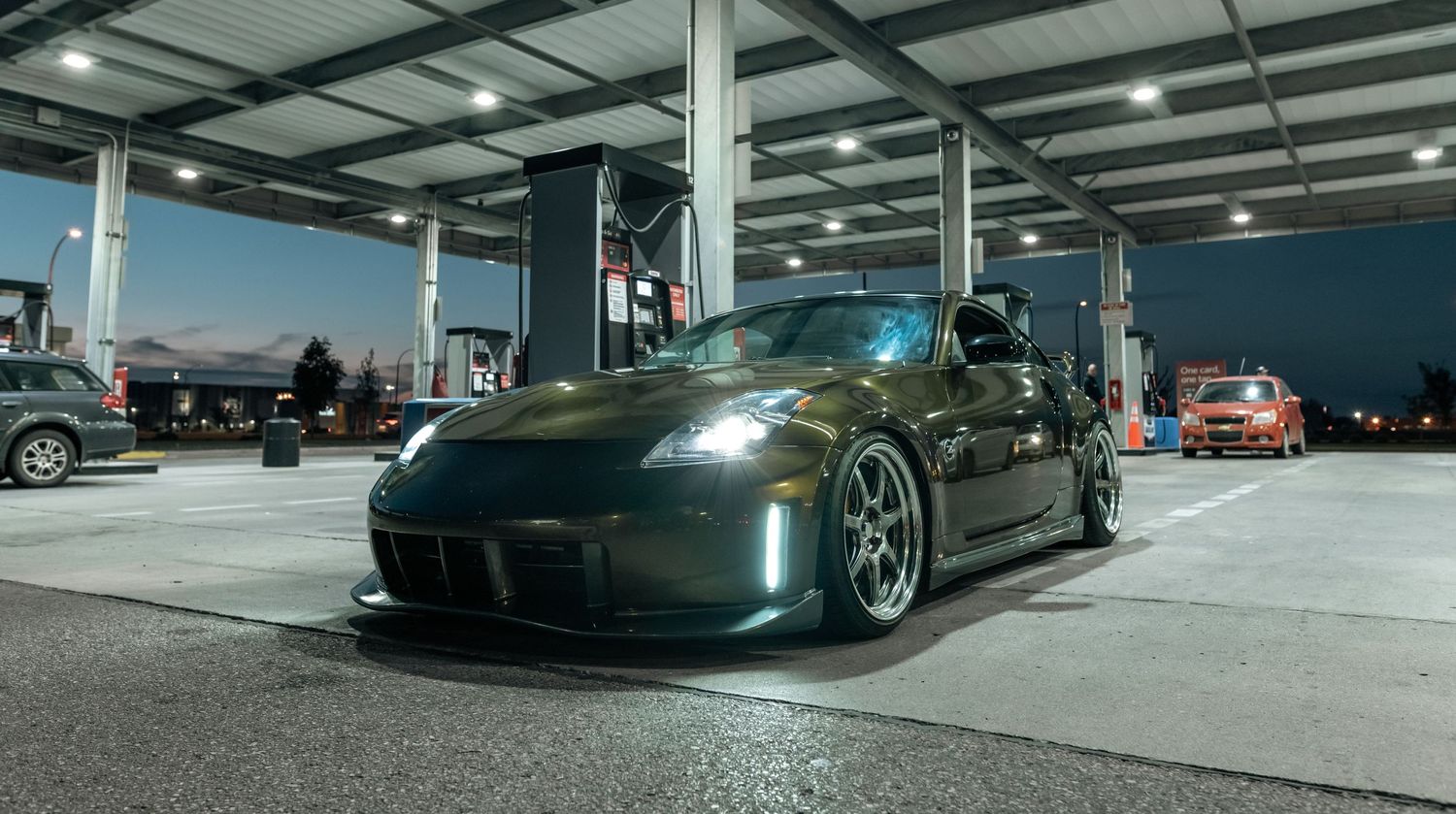 A modified Nissan 350Z with aftermarket wheels parked inside a well-lit garage.
