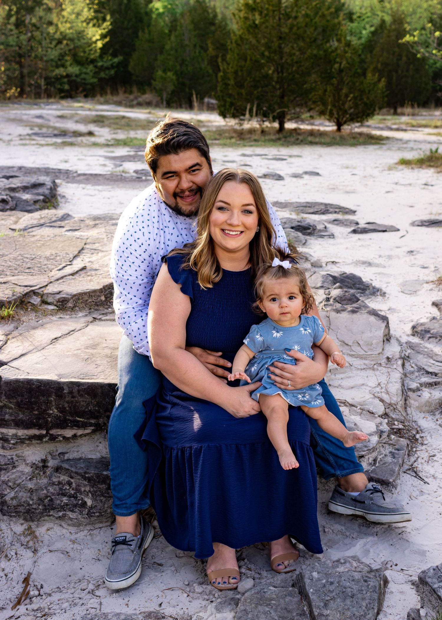 A family poses together on rocky terrain wearing coordinated blue outfits.