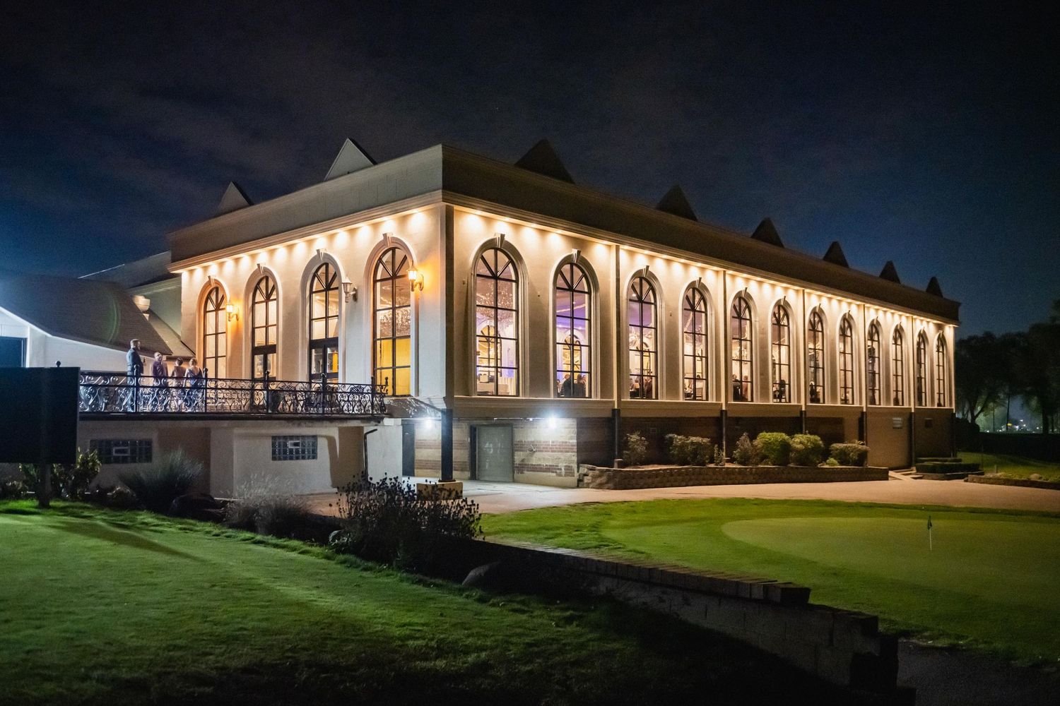 Illuminated grand building with arched windows and columns photographed at night.