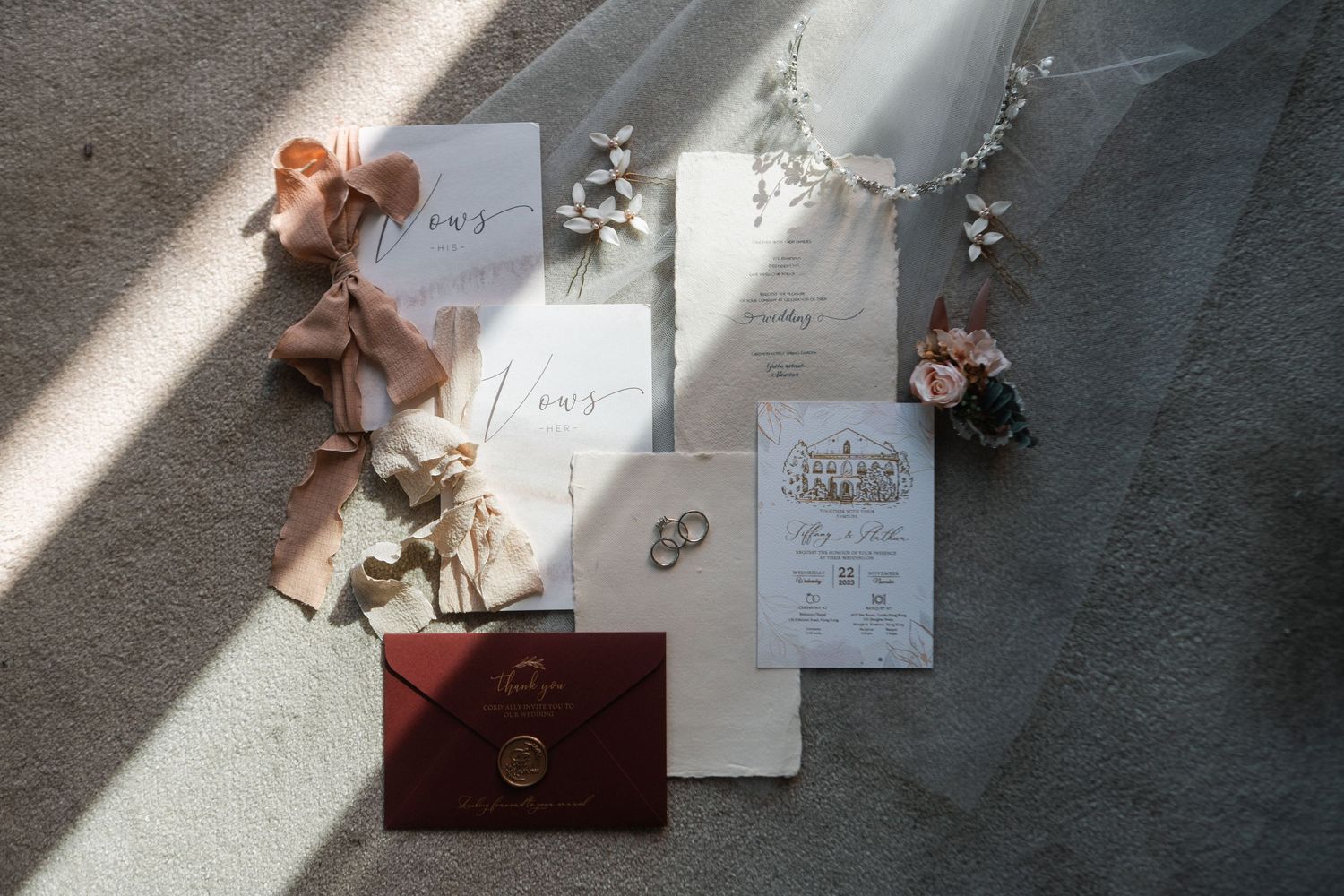 Wedding stationery and invitation suite with dried flowers arranged in natural light on grey fabric.