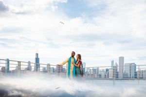 A couple embraces on a rooftop overlooking the Chicago skyline with fog rolling in below.