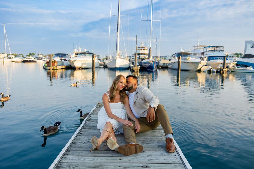 Couple enjoying romantic moment on wooden dock at marina during sunset.