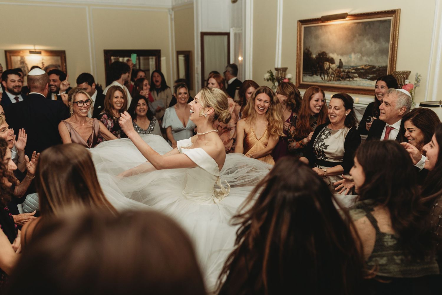 Lively wedding reception party scene with guests dancing and celebrating indoors.