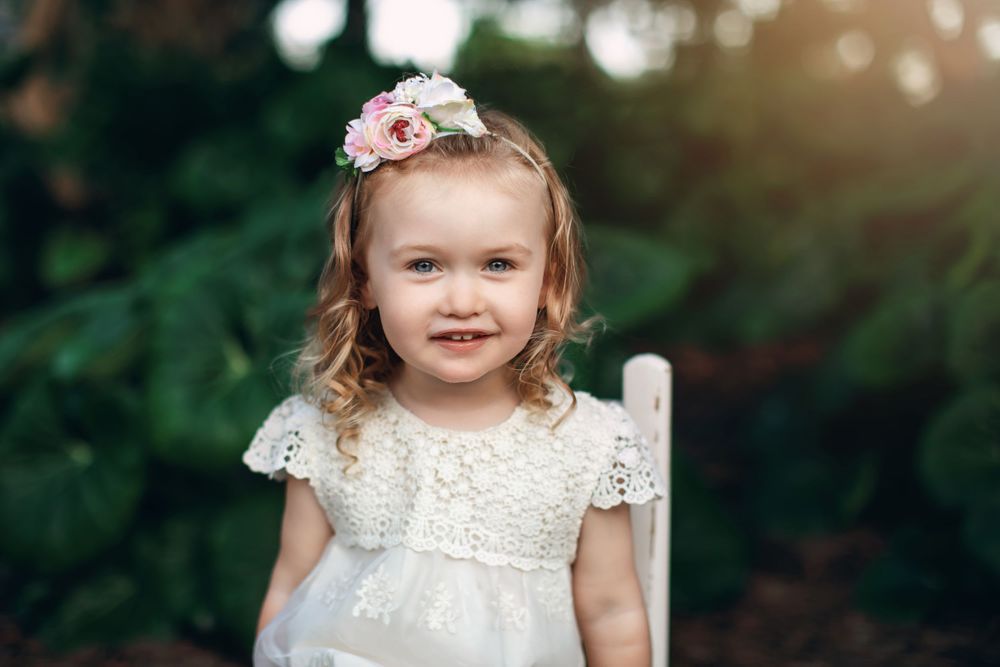 Ethereal outdoor portrait with soft sunlight and floral hair accessory.