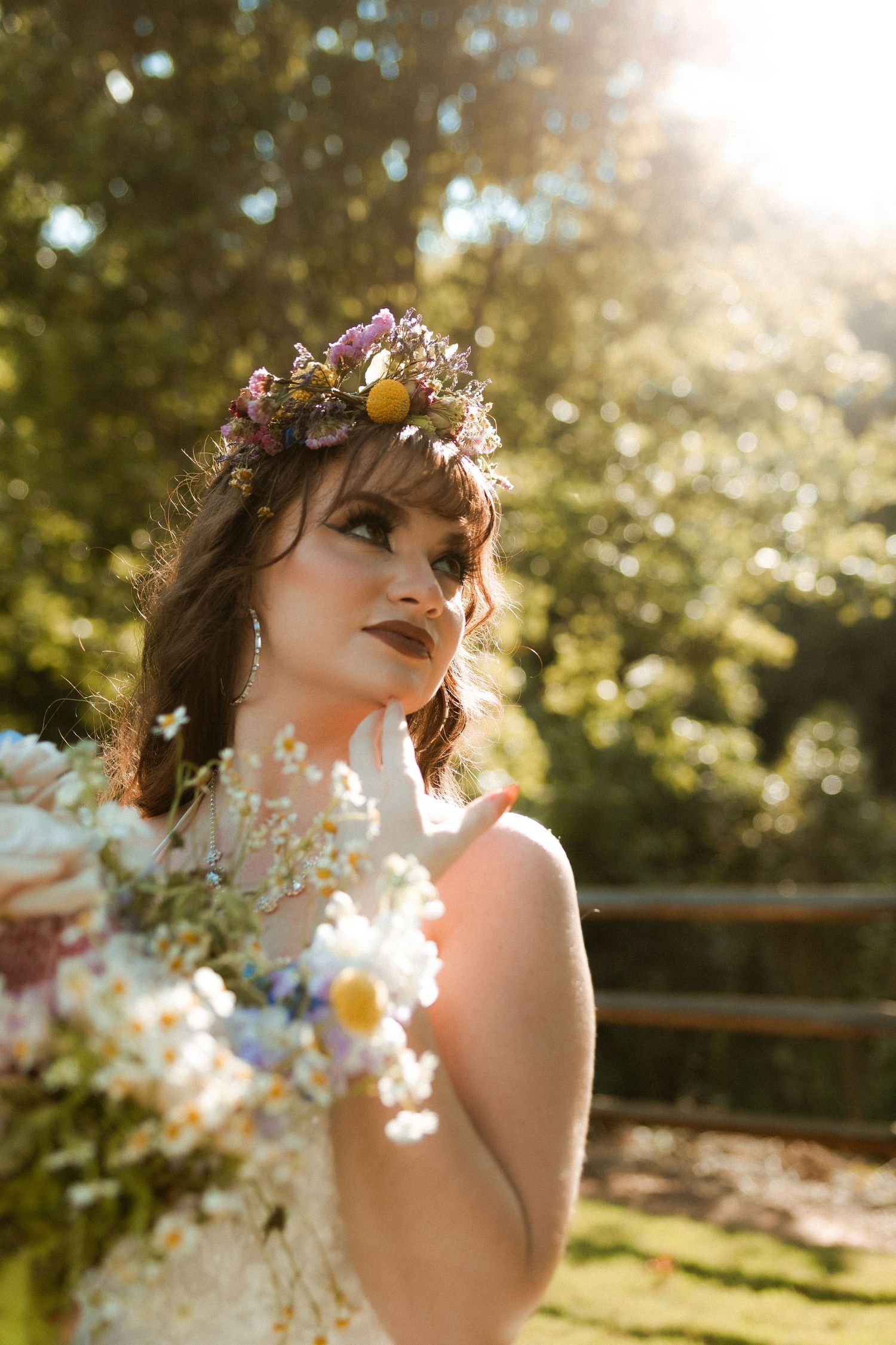 Ethereal portrait of woman wearing floral crown in golden sunlight.