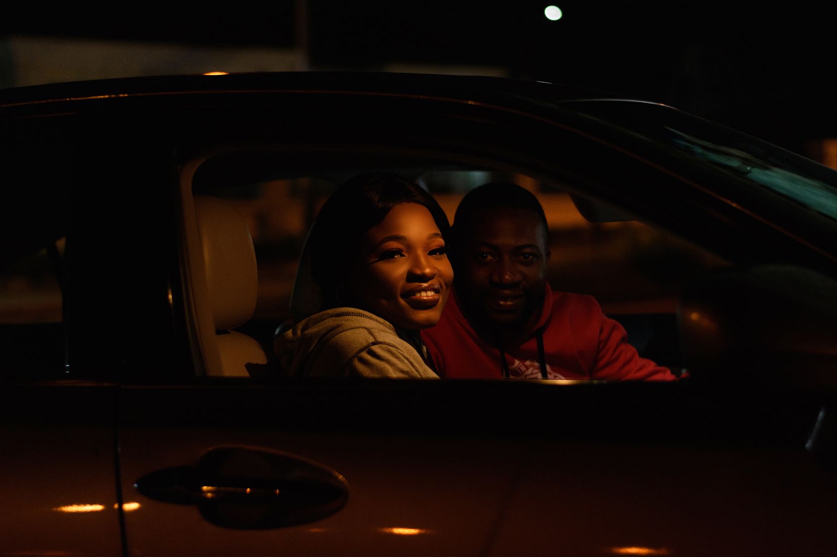 Nighttime photo of two people smiling inside a car.