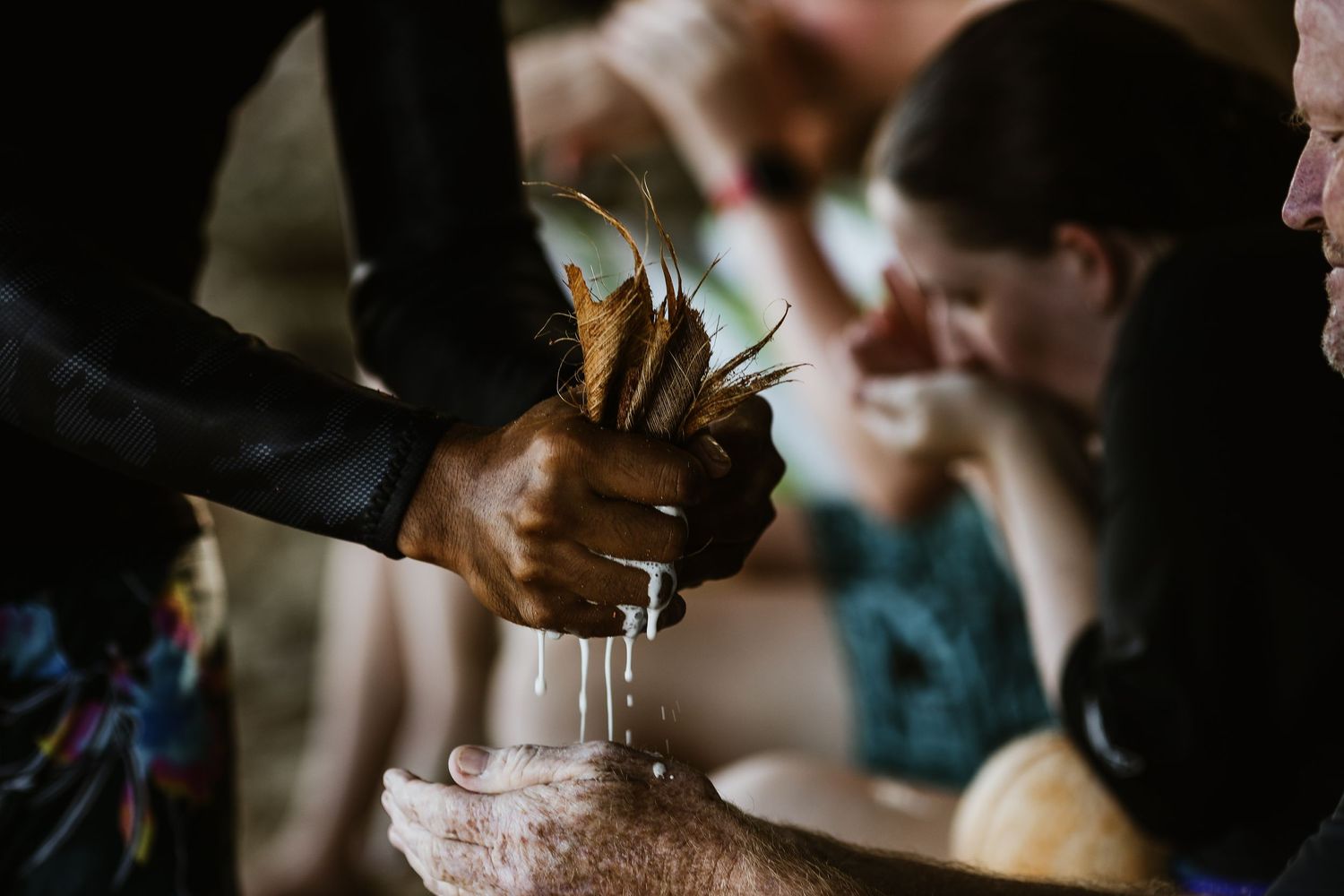 Hands preparing tropical drinks with fresh fruit garnish.