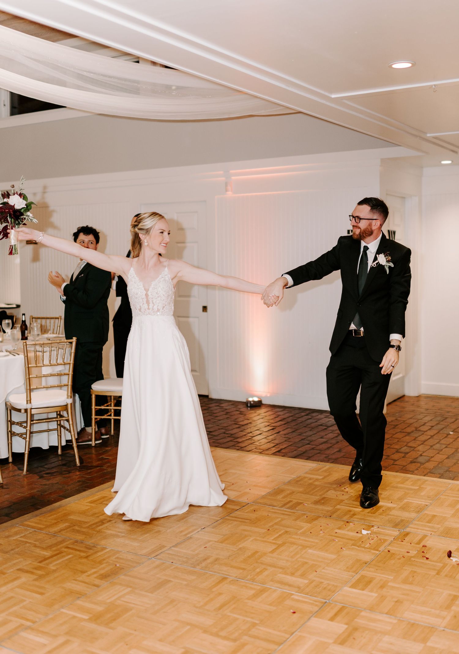 Couples dancing energetically at wedding reception with white and gold decor.