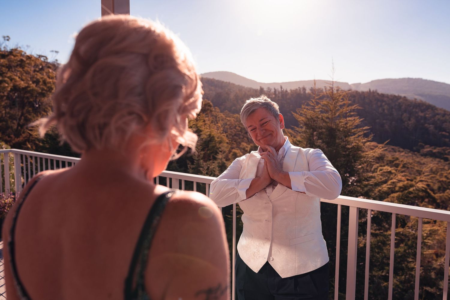 Couple sharing a moment on outdoor balcony with mountain landscape in background.
