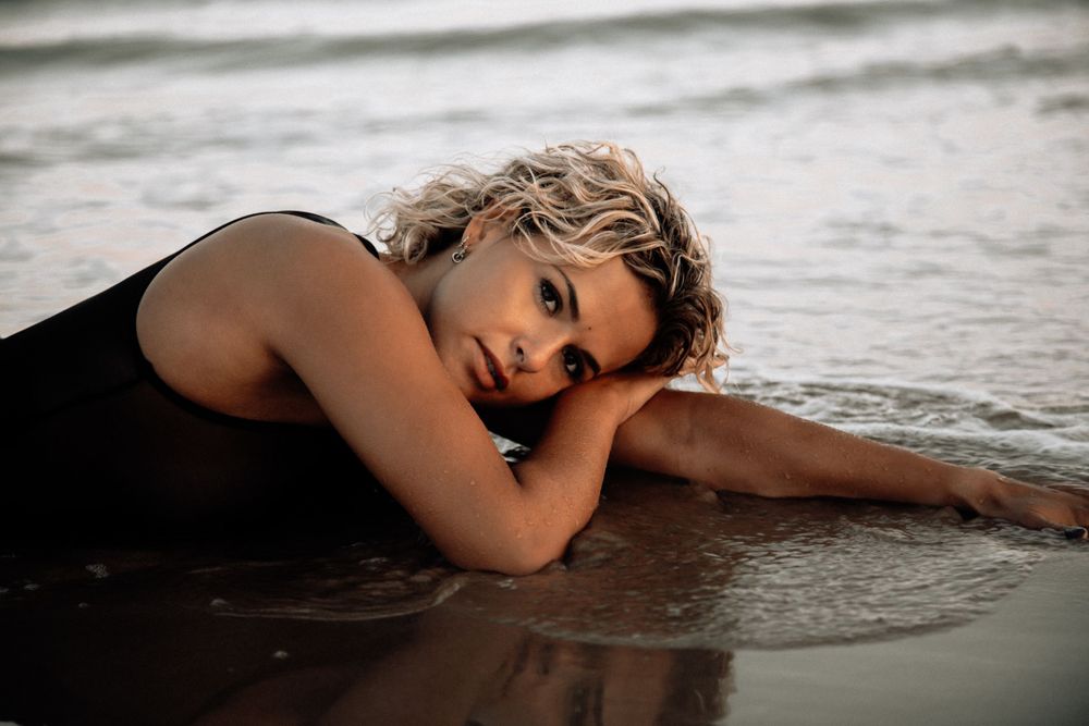 Vrouw in de branding tijdens een boudoir shoot aan zee, een unieke ervaring om je zelfvertrouwen en natuurlijke schoonheid vast te leggen!