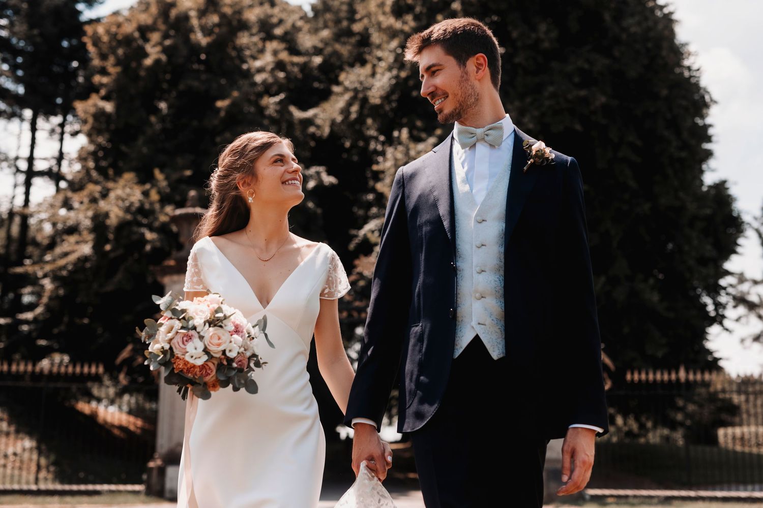 A romantic wedding portrait of newlyweds outdoors with the bride holding a colorful bouquet.