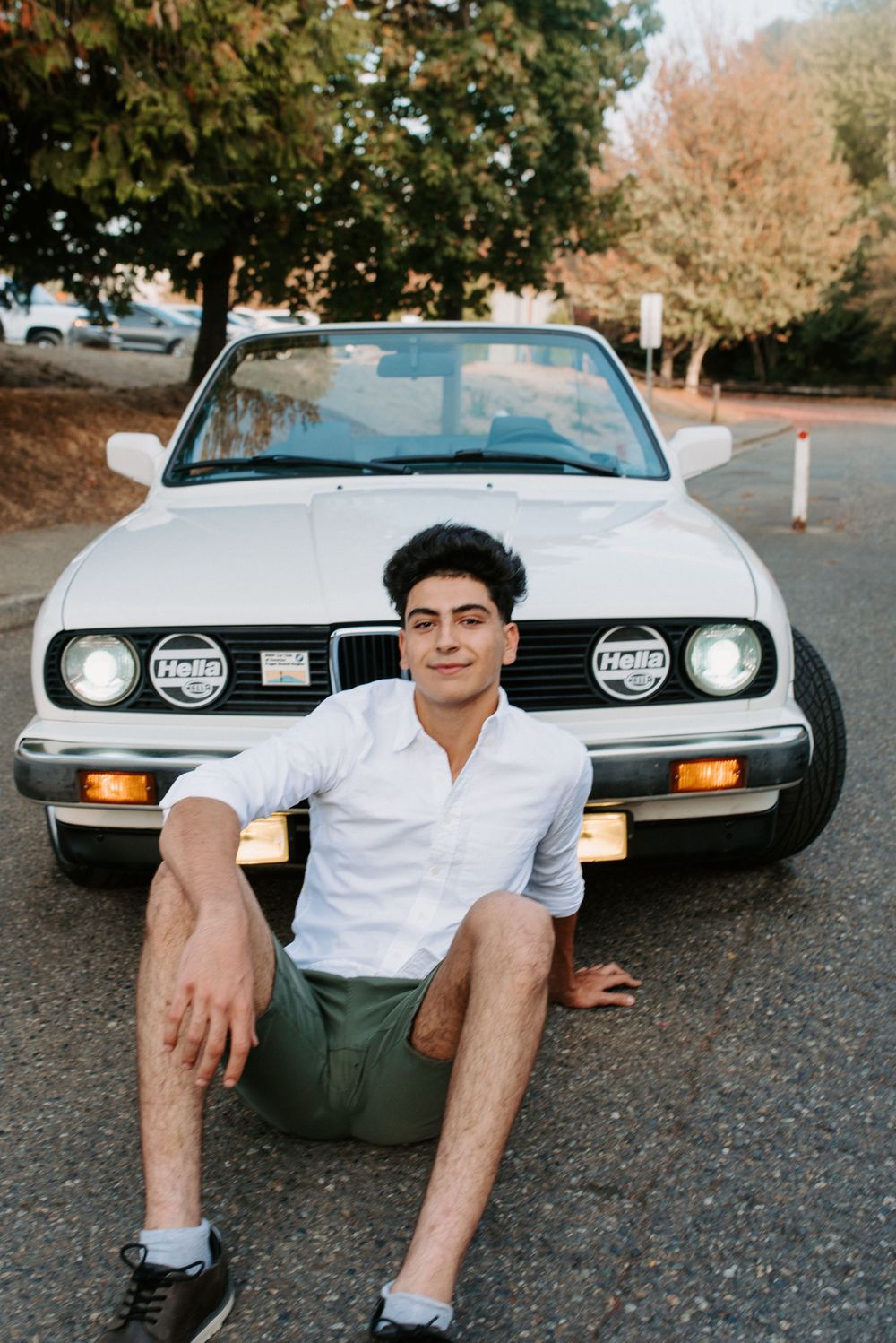 Casual portrait session with vintage car featuring classic headlights and chrome details.