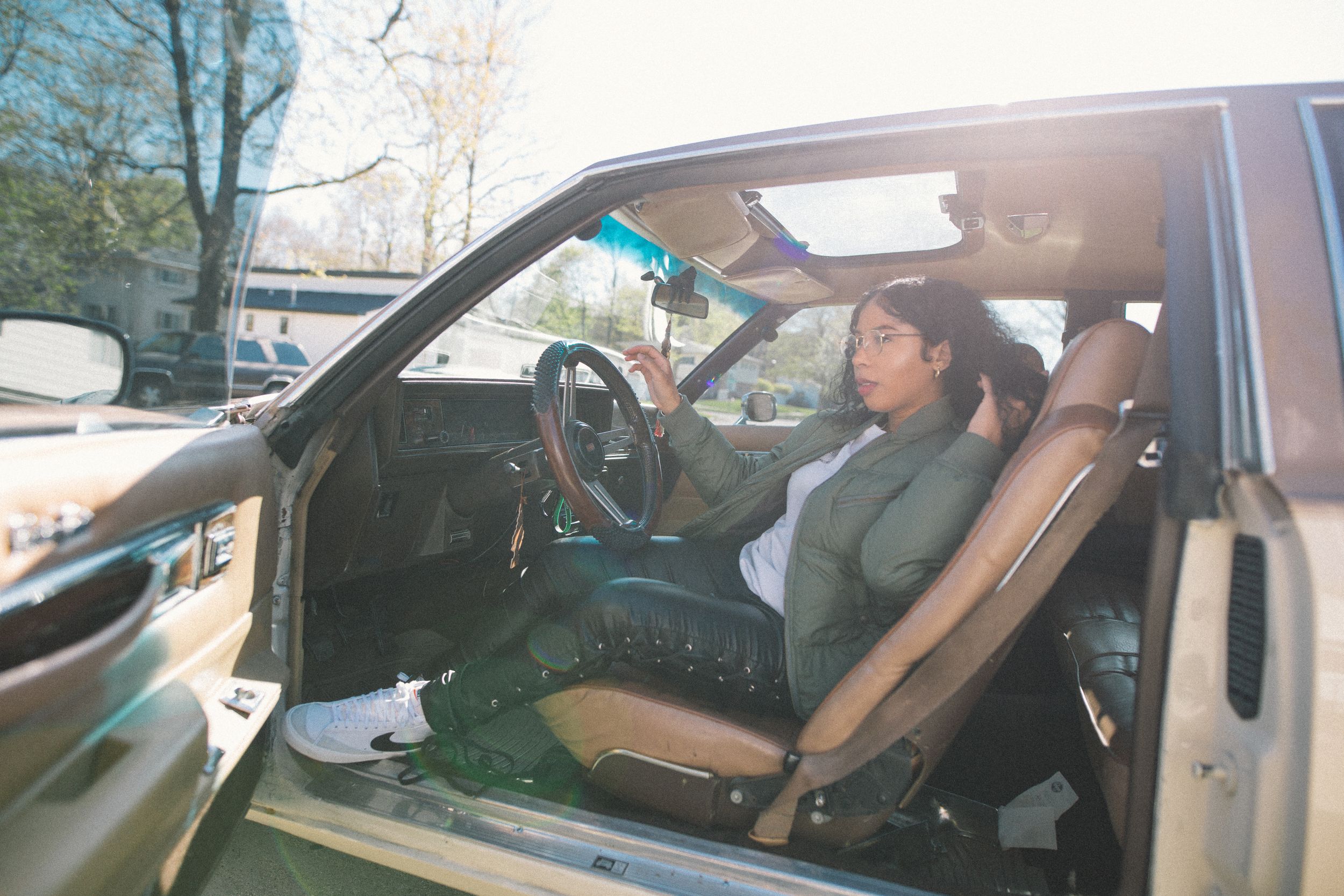 Person and dog sitting in car with open door showing casual footwear.
