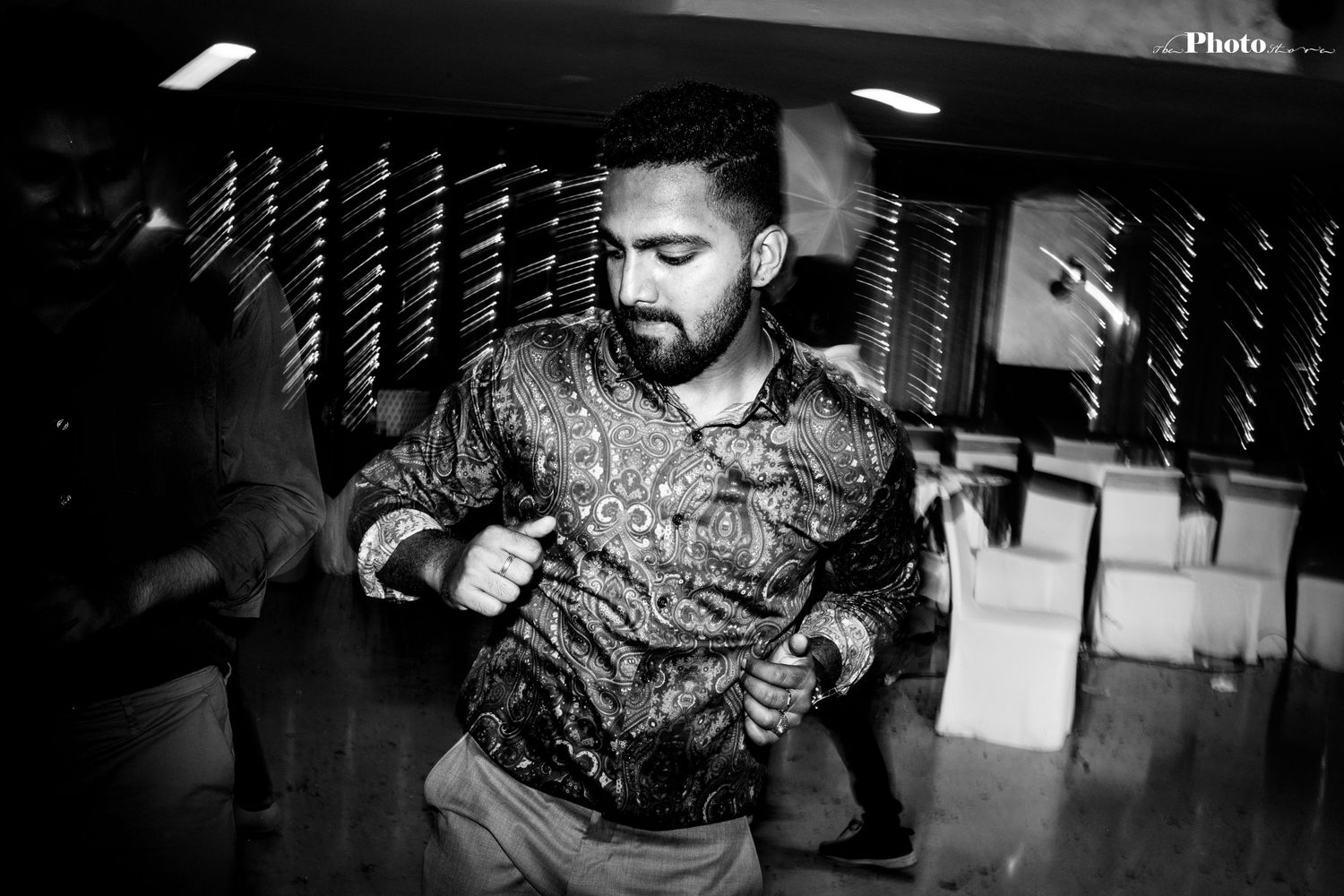 Black and white photo of a person dancing energetically at a party with motion blur effects.