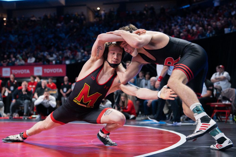Intense wrestling match action on a red competition mat.