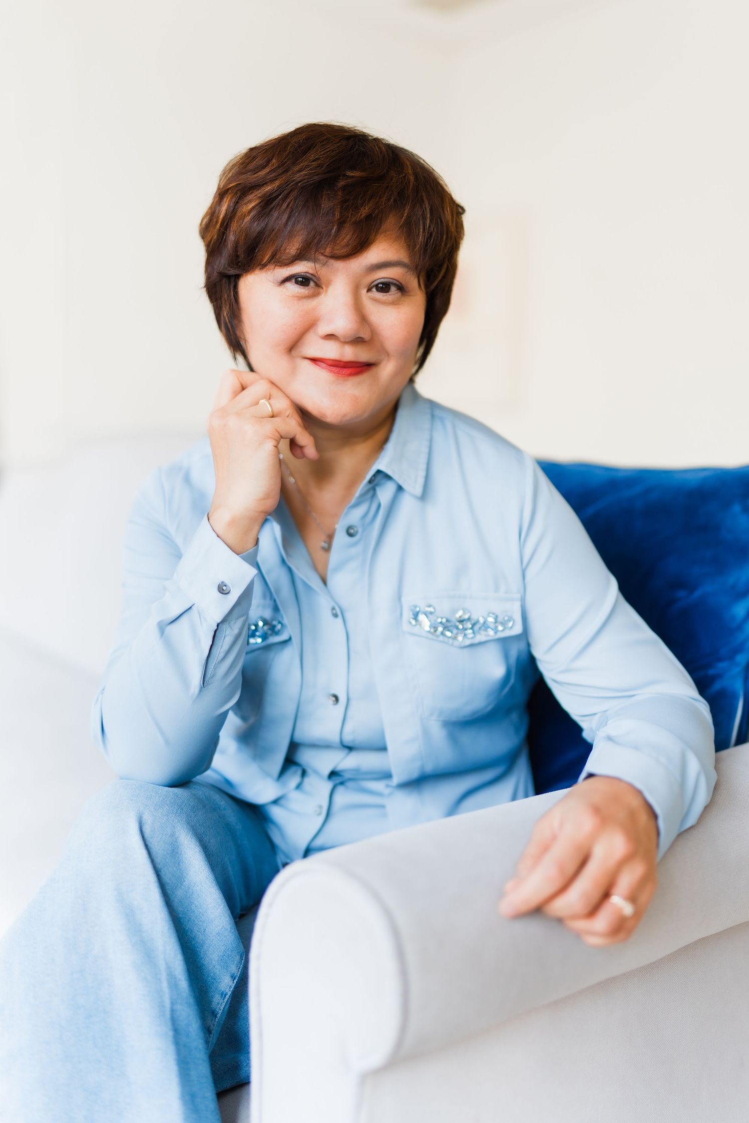 Person in light blue uniform sitting relaxed on white couch with blue pillow.