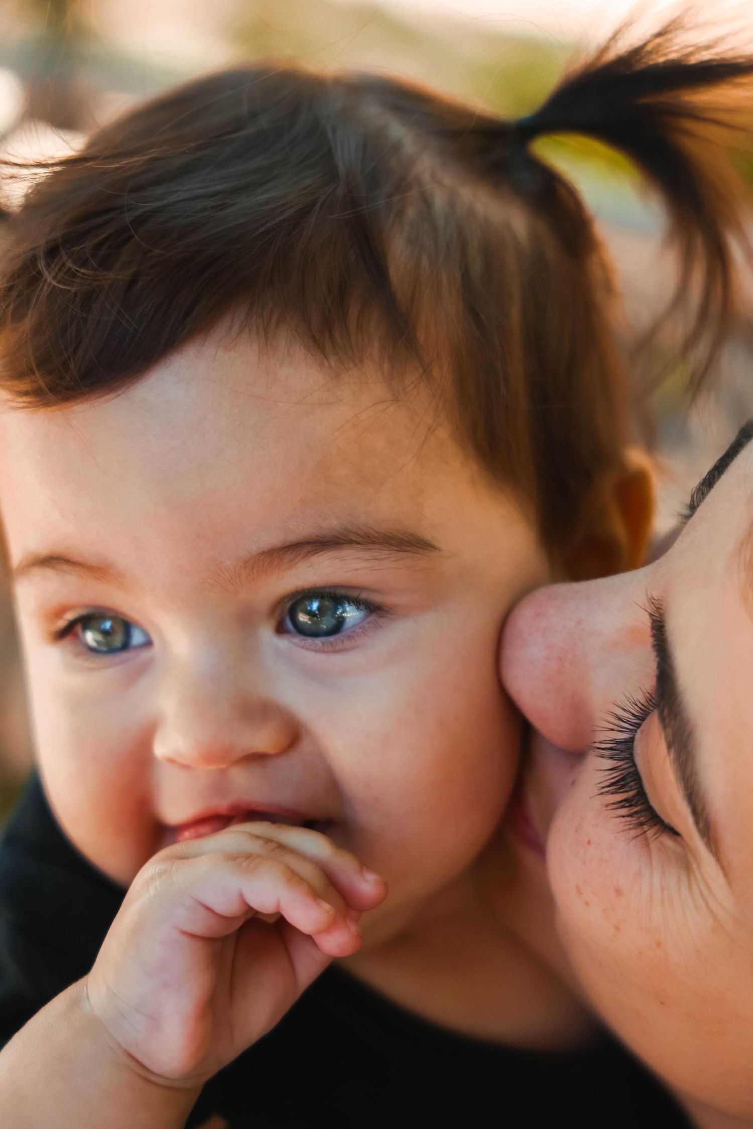 Sweet close-up of baby with chubby cheeks being kissed.