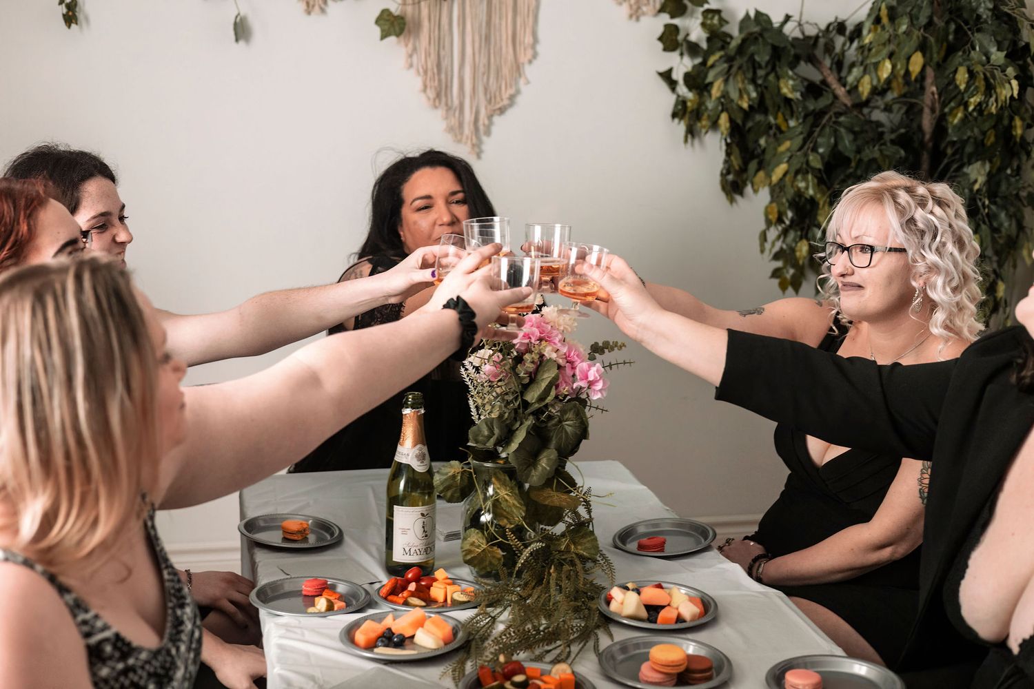 Group of friends raising glasses in celebration at a decorated indoor gathering.