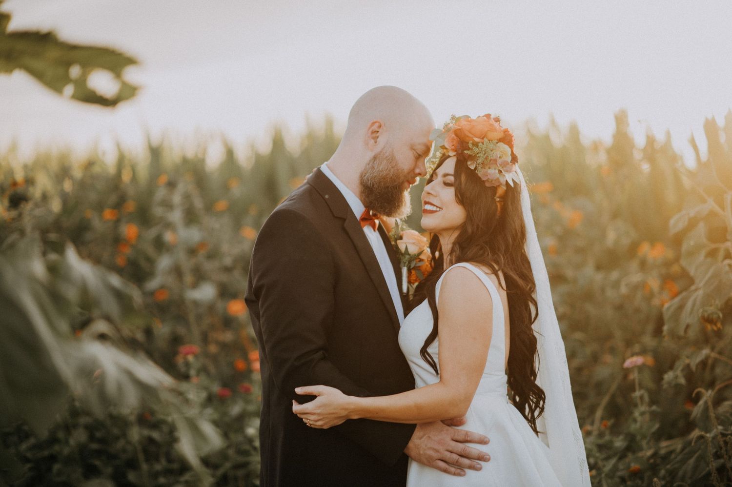 A couple shares an intimate moment at sunset in a field with golden light.