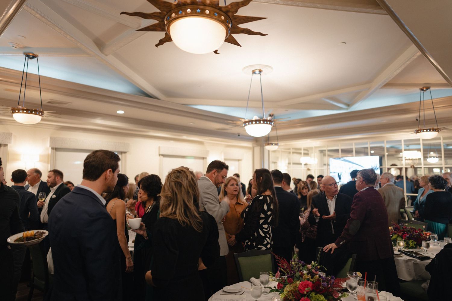 An elegant indoor reception space filled with guests and ambient lighting.
