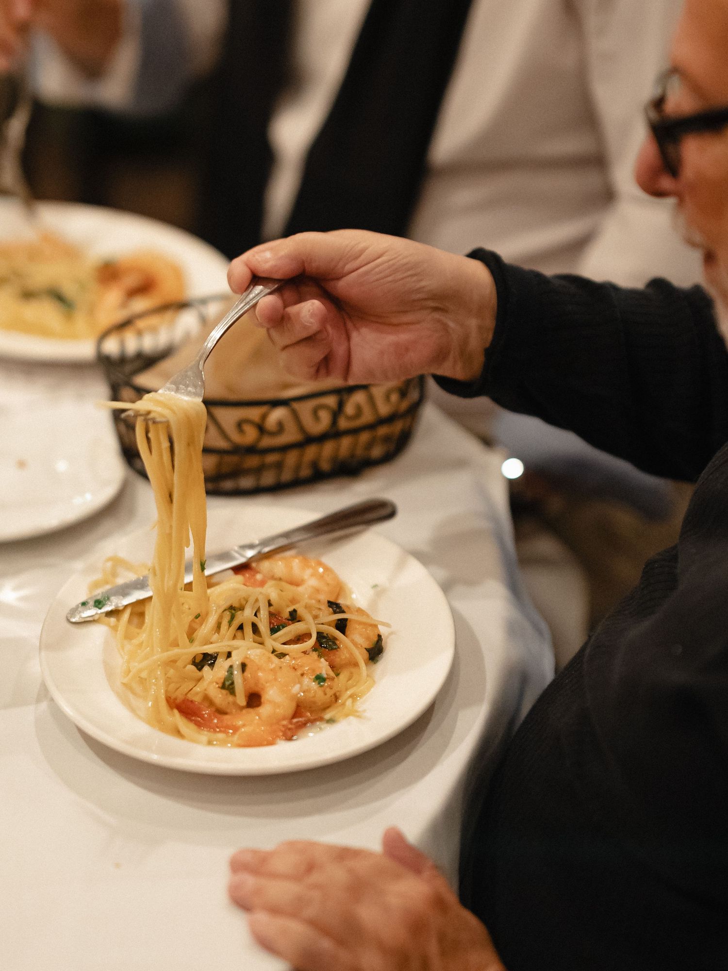 Close up of pasta being served on white plates at a formal dinner.