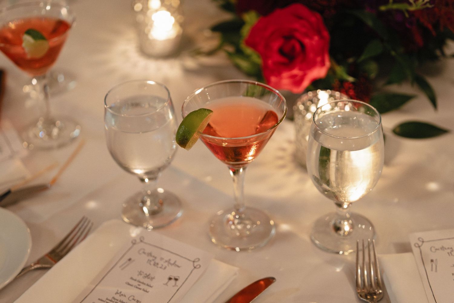 Elegant table setting with cocktails, wine glasses and candlelight at a formal event.