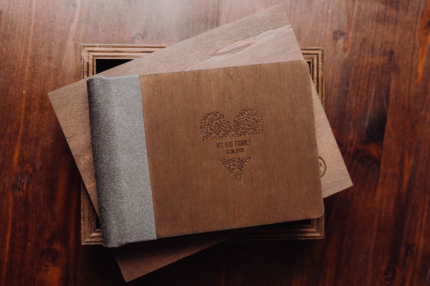 Brown leather photo albums with decorative designs stacked on a wooden surface.