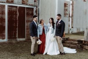 Wedding party posing casually against rustic corrugated metal wall for candid photo series.
