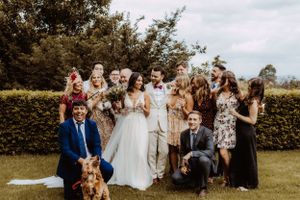 Wedding party group photo in an outdoor garden setting with natural lighting.