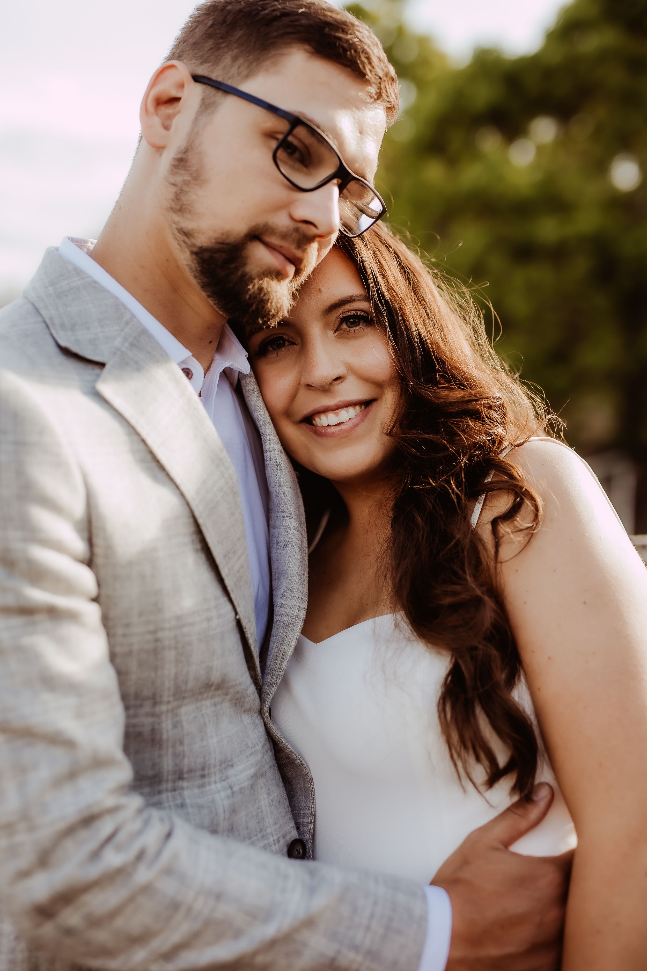 Romantic wedding couple embracing outdoors in soft natural lighting.