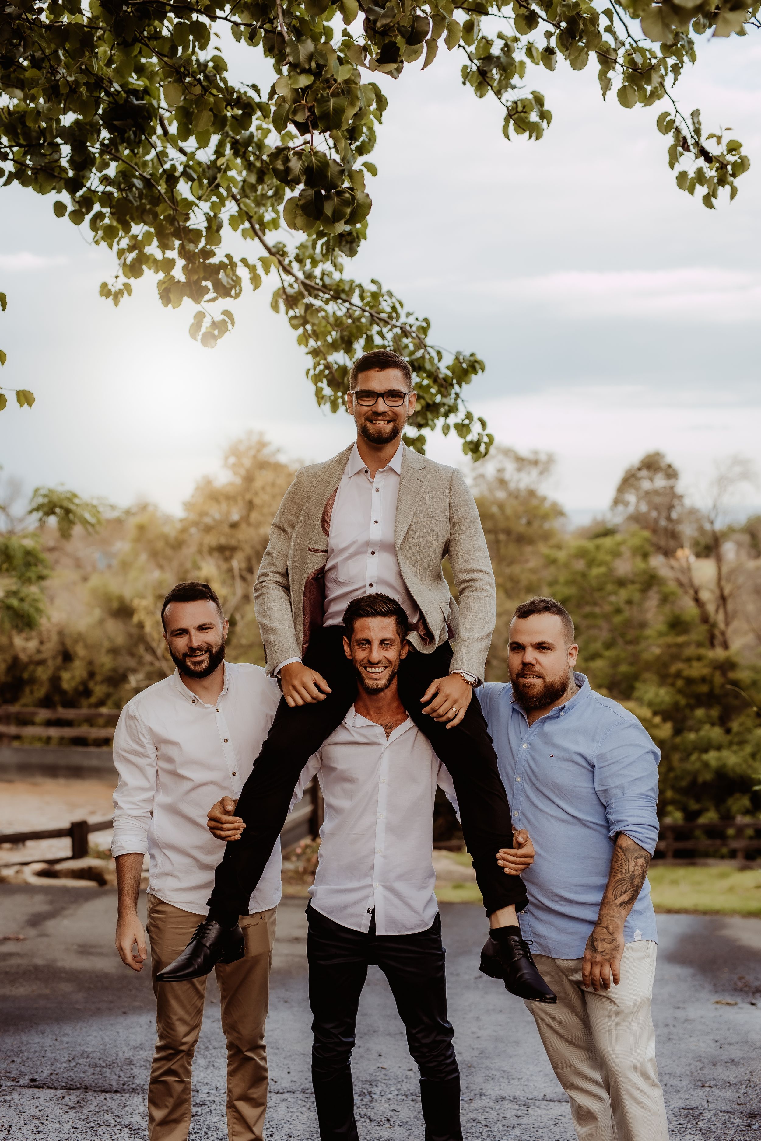 Group of groomsmen laughing and having fun outdoors during wedding photoshoot.