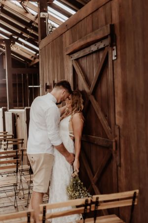 An intimate wedding moment captured inside a rustic wooden barn with natural lighting.