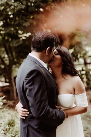 A romantic wedding moment captured in a garden setting with soft natural lighting.