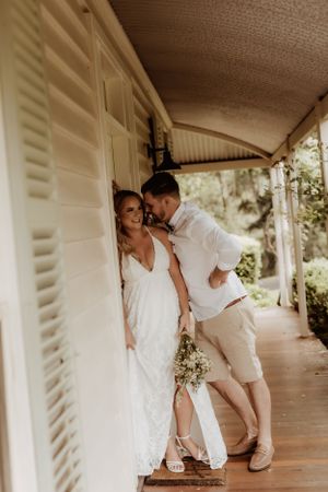 A playful wedding photoshoot on a white wraparound porch with rustic architectural details.