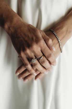 Close-up of hands wearing elegant wedding rings against a white background.