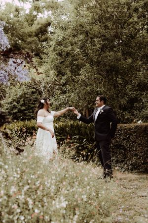Romantic wedding couple walking through wildflower field in dreamy natural lighting.