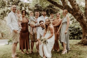 Wedding party laughing together during outdoor photo session under tree branches.