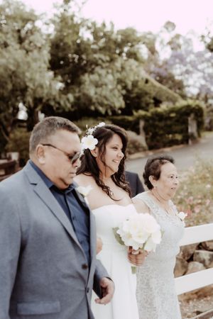 Wedding couple sharing tender moments in garden setting with white fence backdrop.