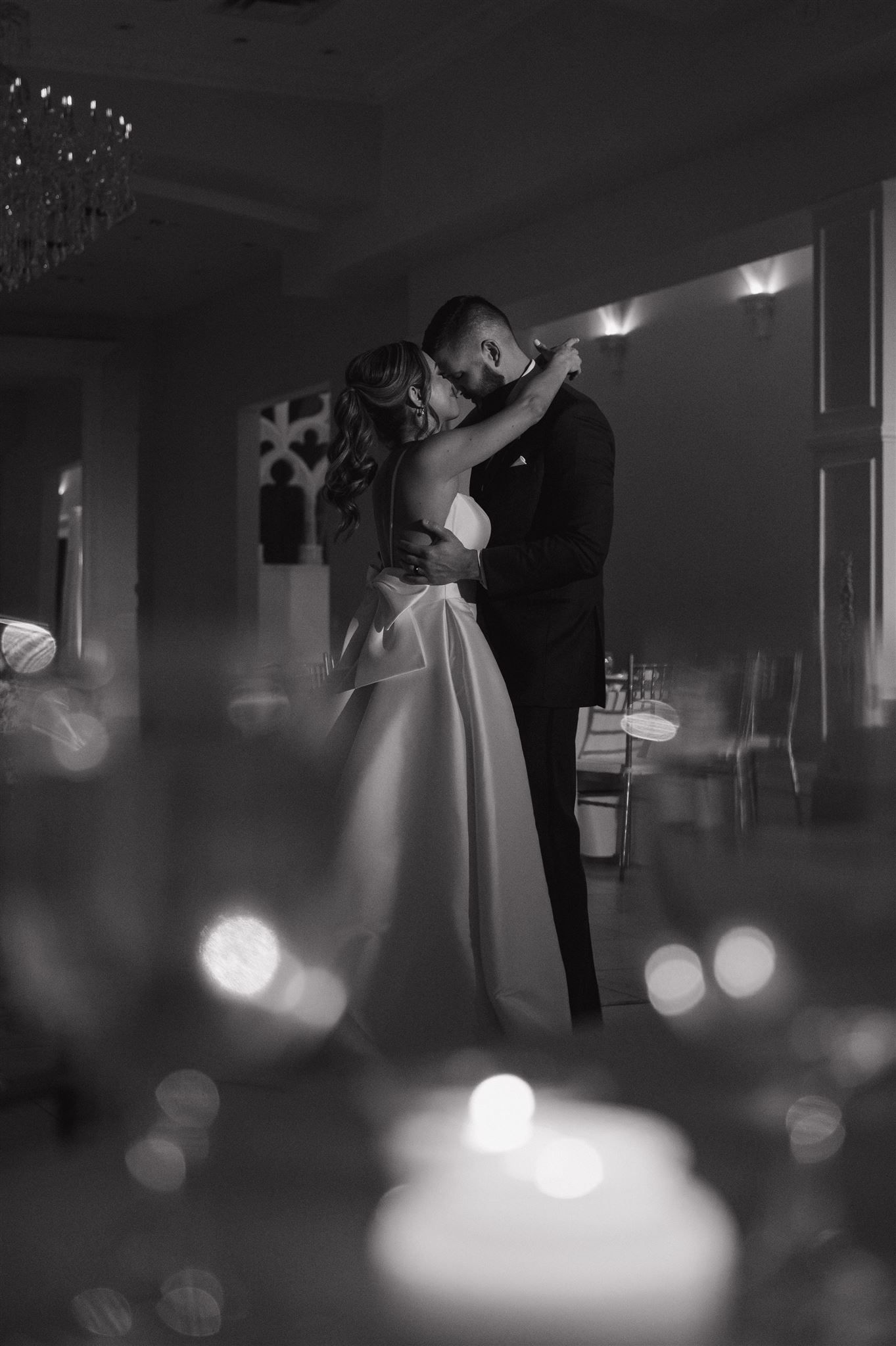 An intimate black and white photo of a bride and groom embracing during their first dance.