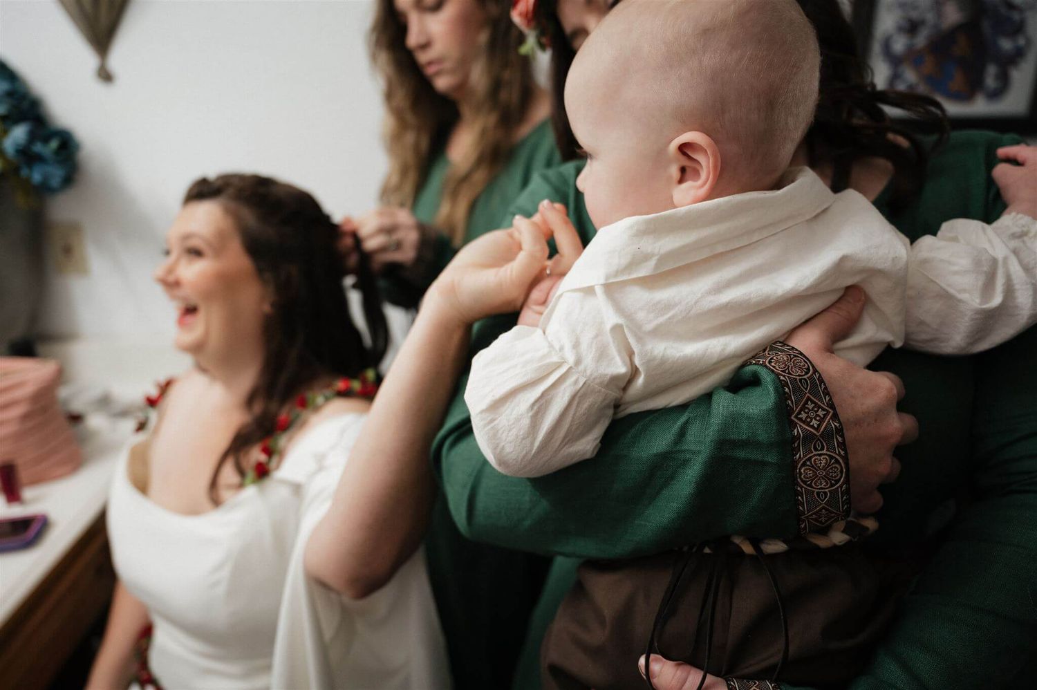 A small child in white clothing is held during what appears to be a medieval-themed gathering.