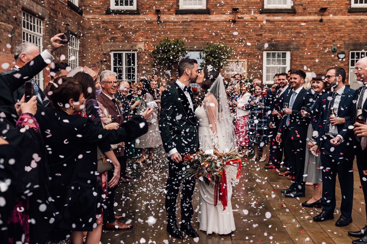 bride and groom kissing under confetti
