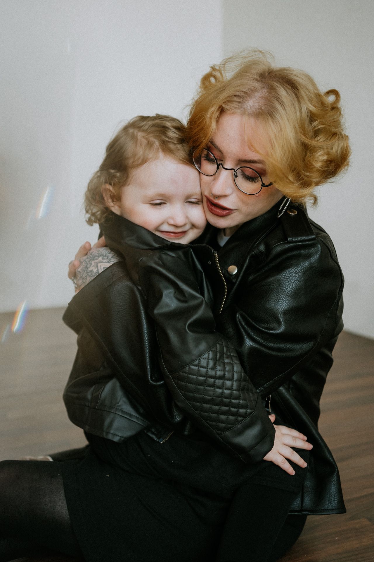 Mother and child sharing joyful moment in matching leather jackets indoors.